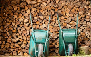 how many wheelbarrows in a cord of wood - two wheelbarrows in front of a stack of firewood